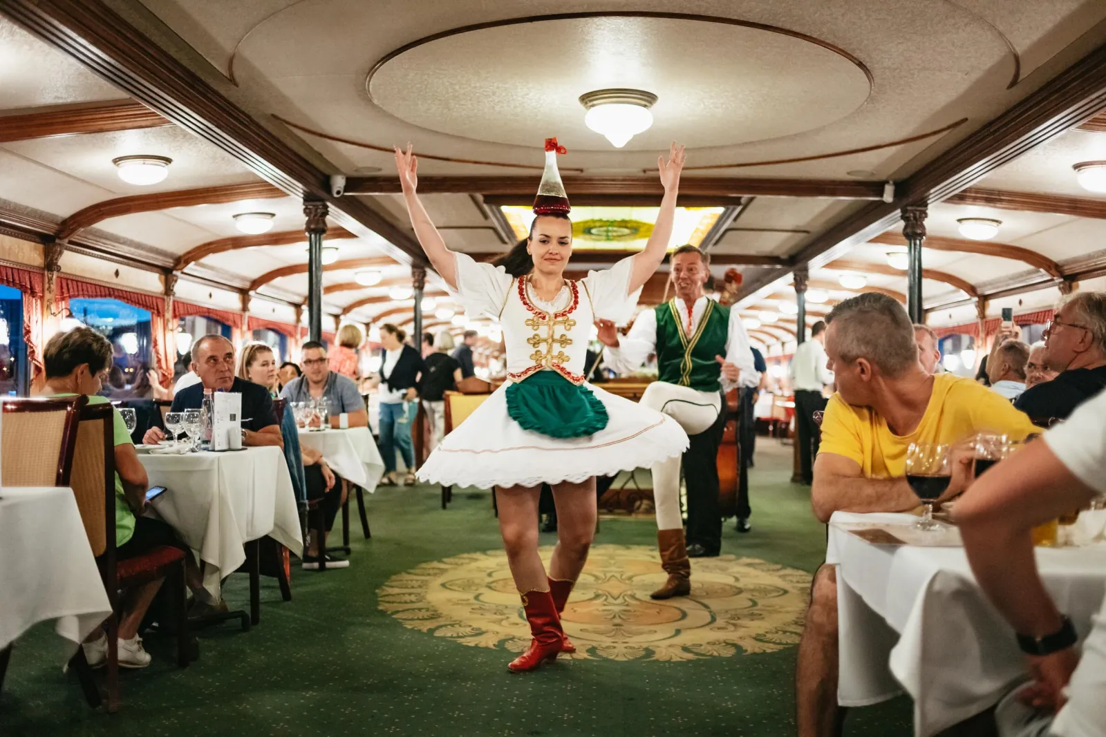 A dancer in folk costume in the aisle of the dining room
