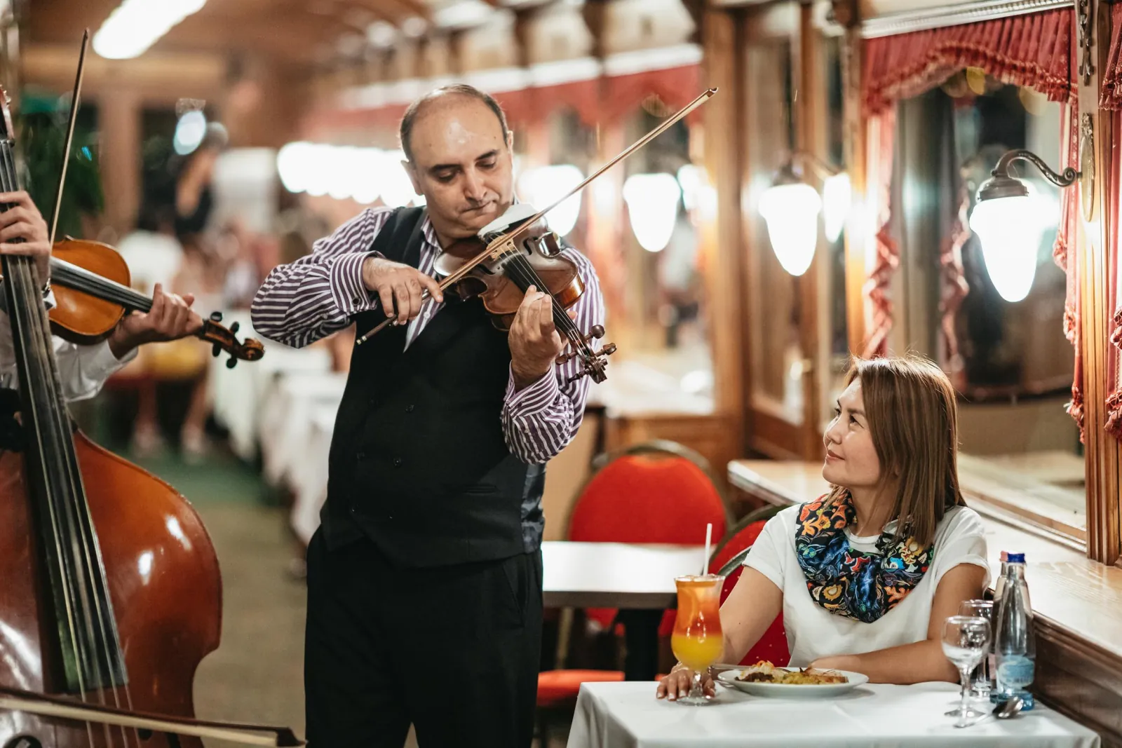 A violinist and double bass player beside a guest’s table