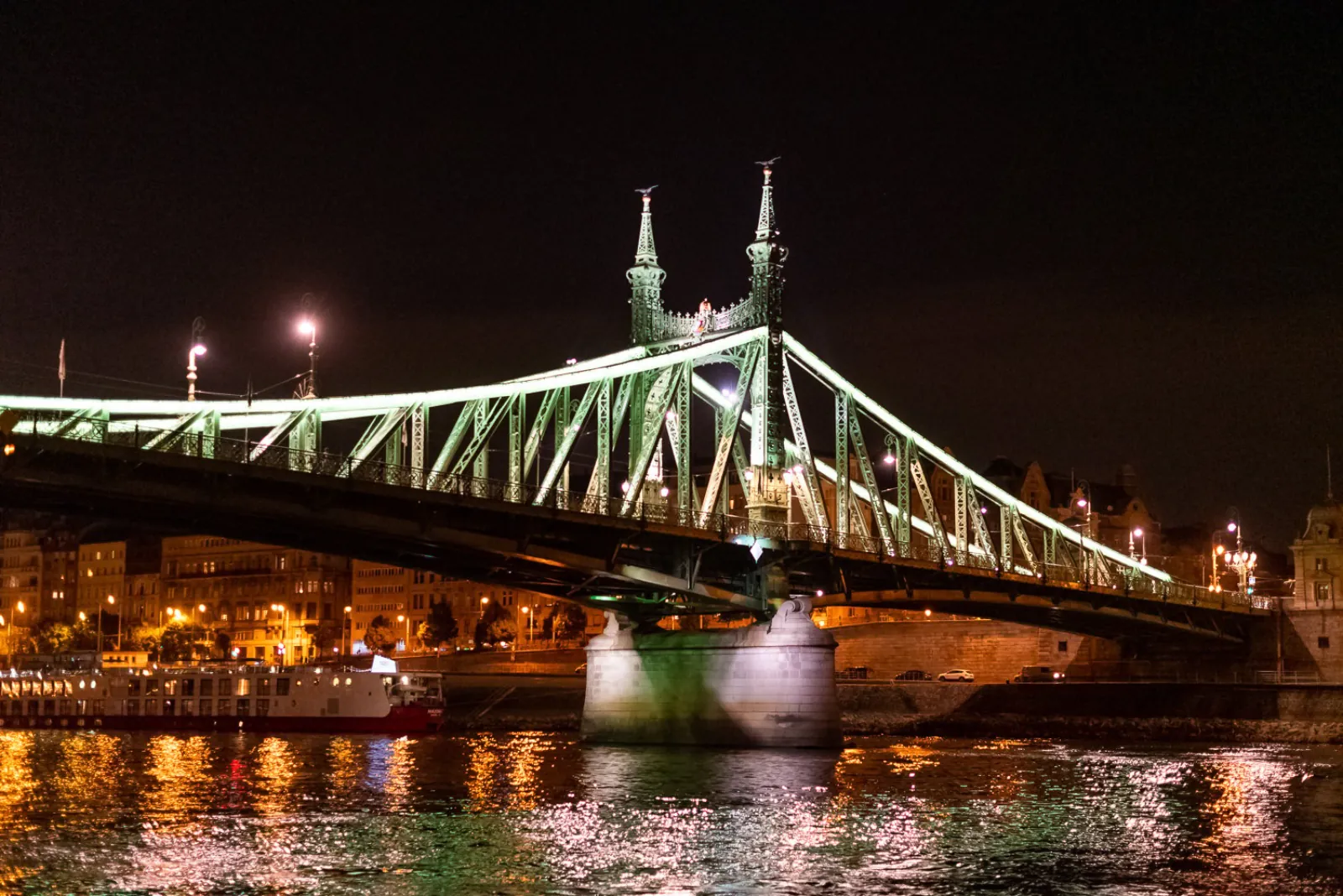 Liberty Bridge lit in green over the river