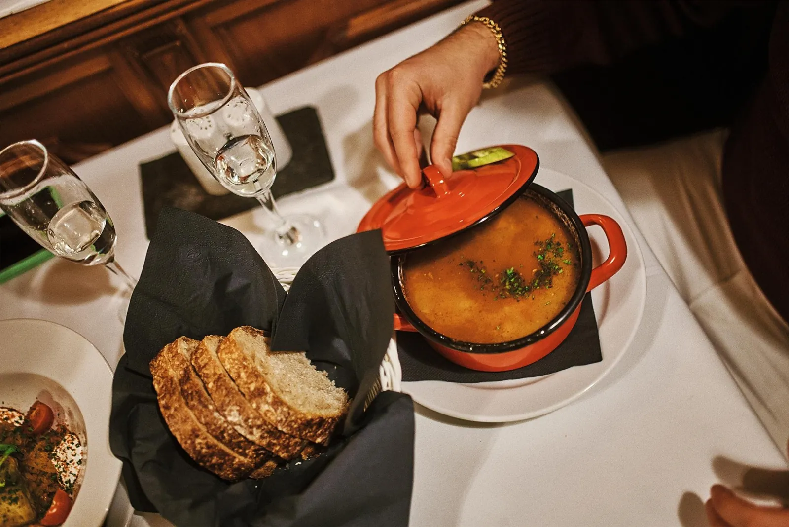 Goulash in a pot with bread and a glass of wine