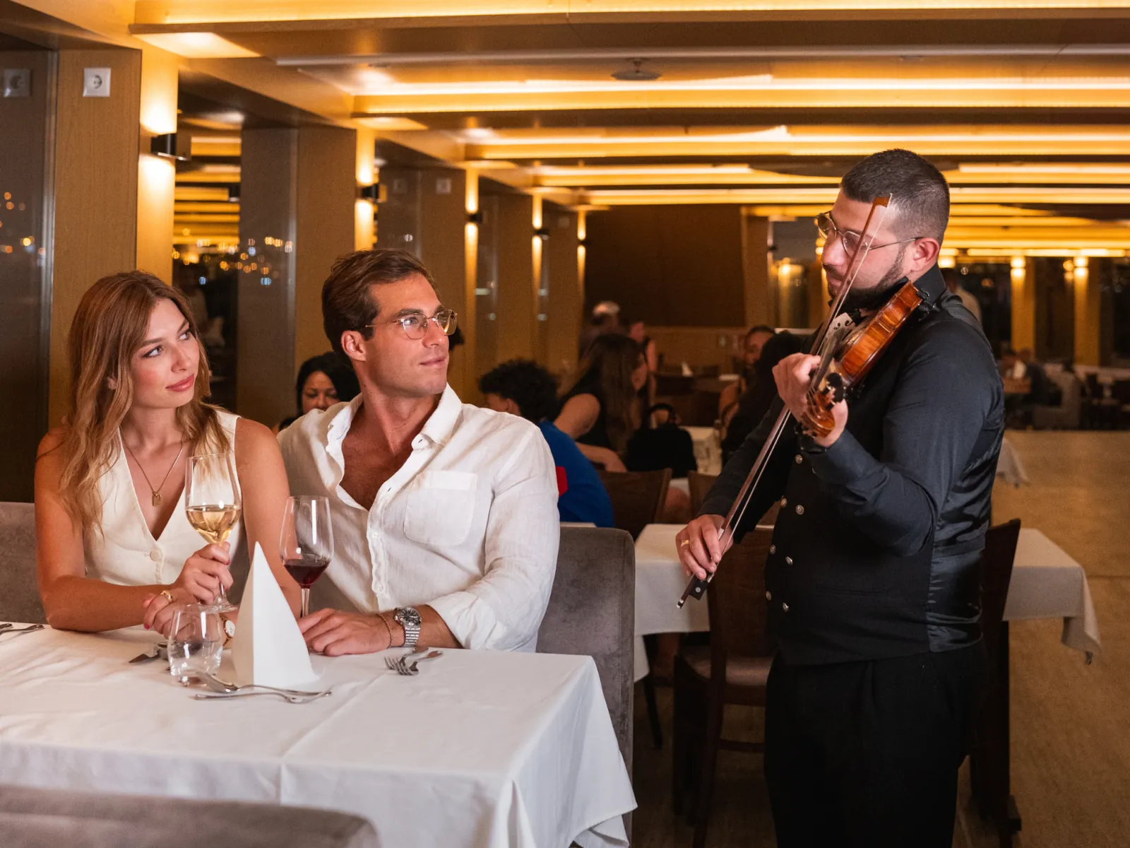 A violinist playing at a couple’s table during dinner
