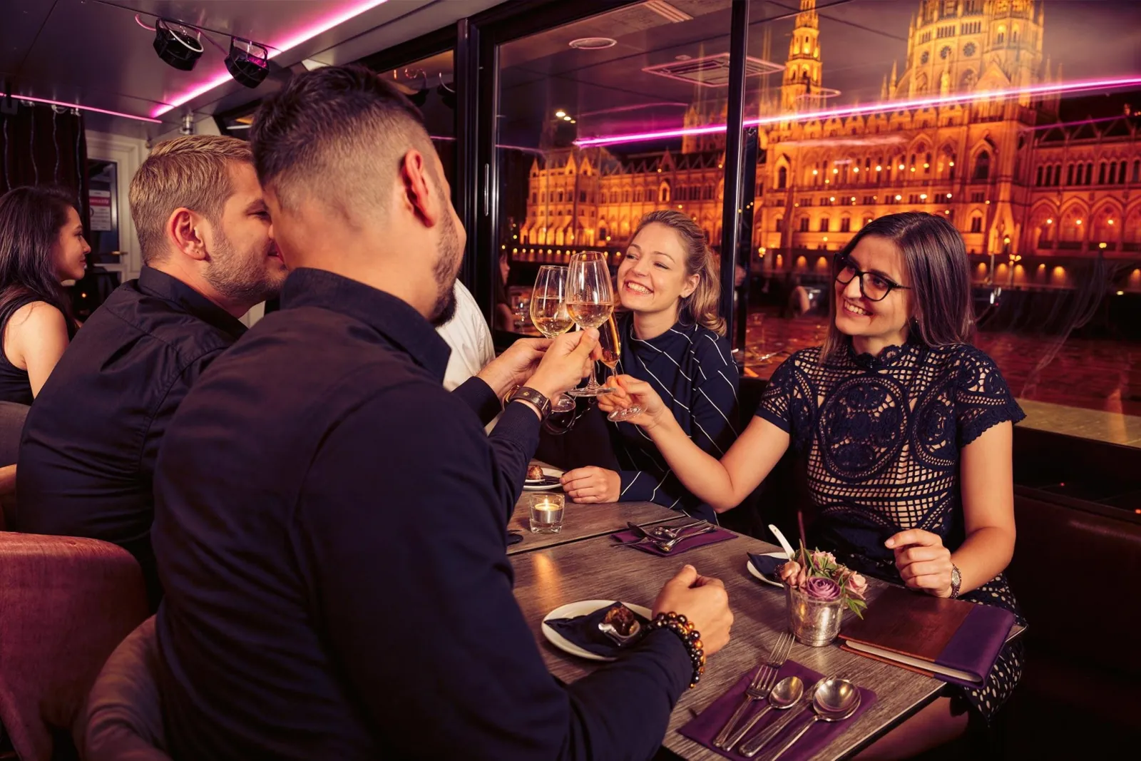 Friends raising glasses at dinner with the Parliament outside