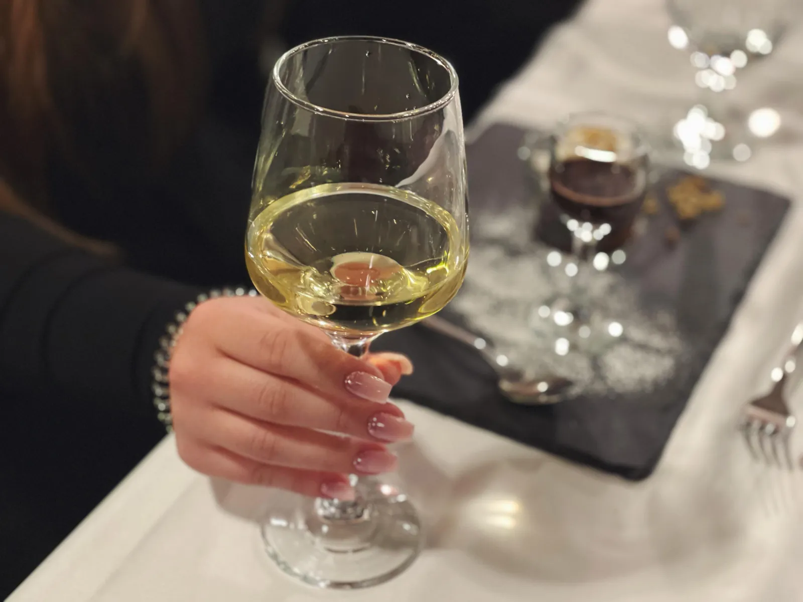 A glass of white wine held over the table