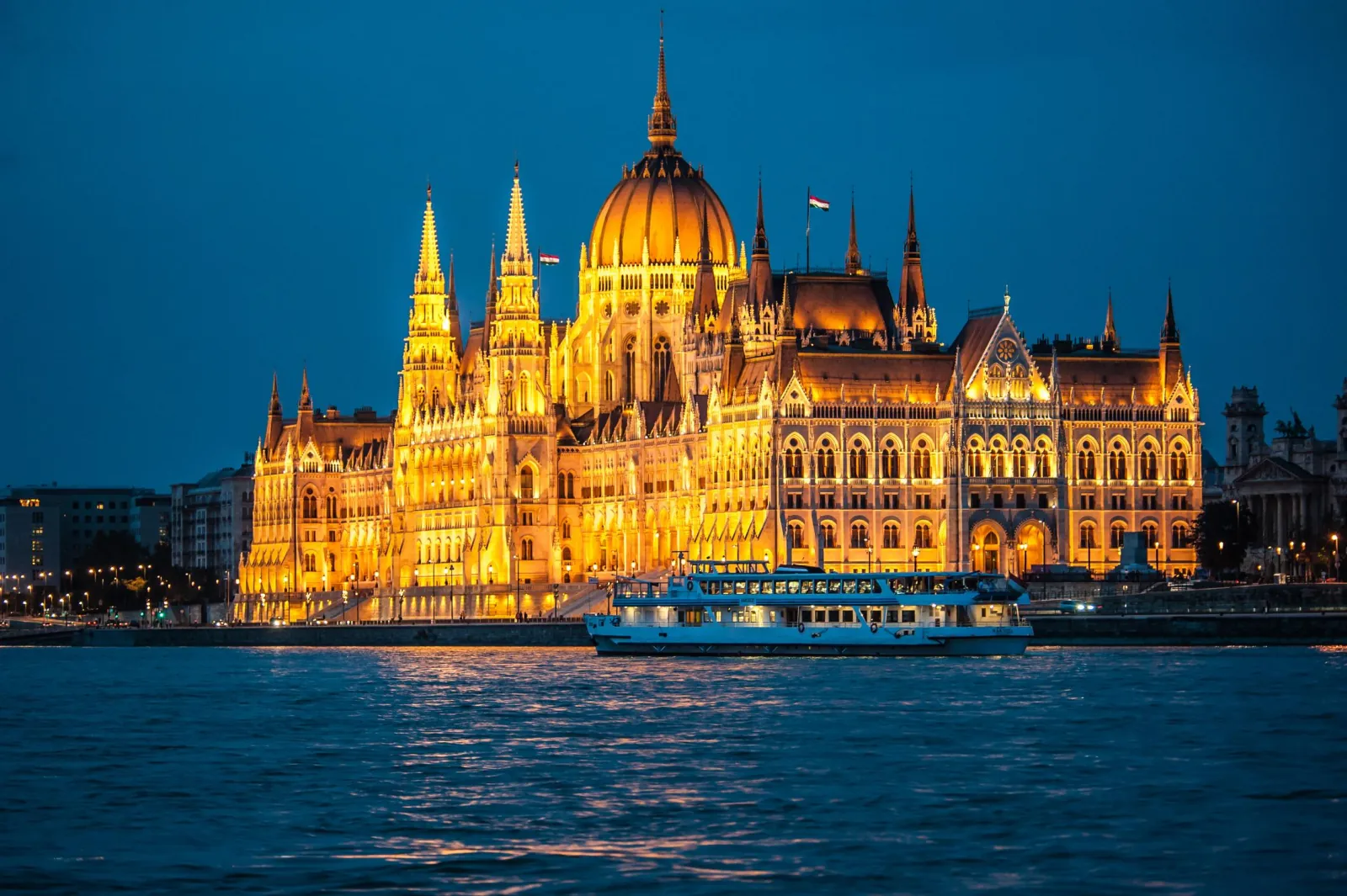 The Parliament floodlit with a sightseeing boat passing