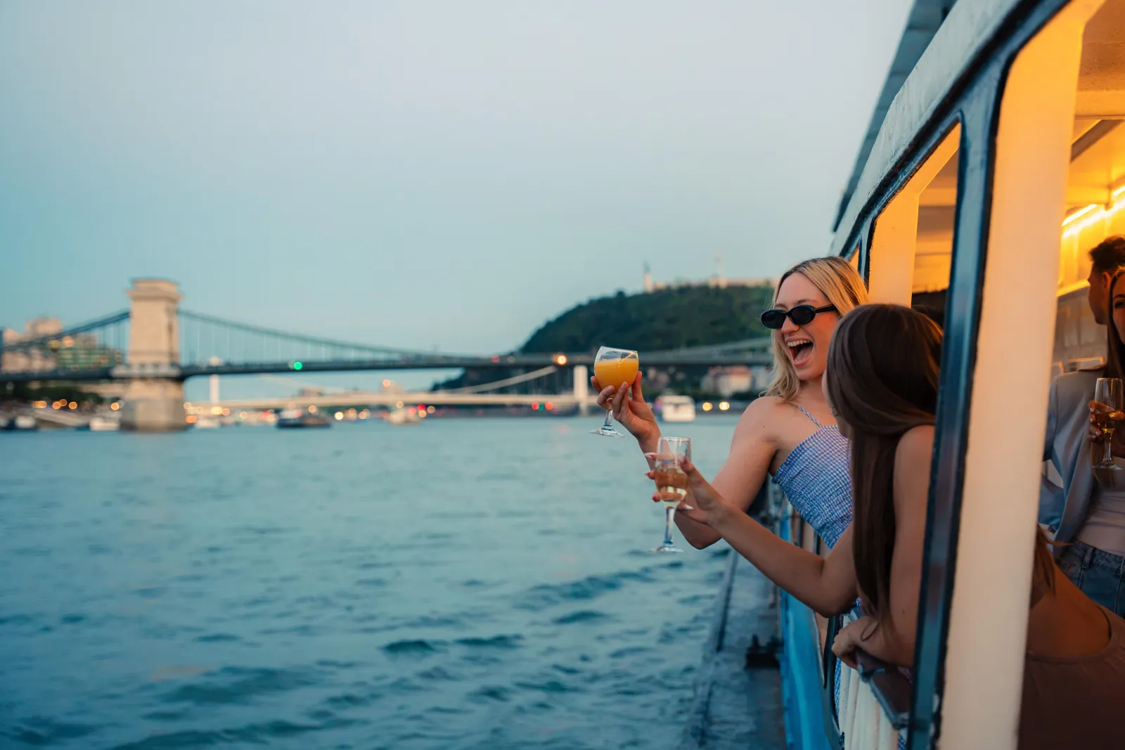 A guest leaning out of the window with a drink, Chain Bridge ahead