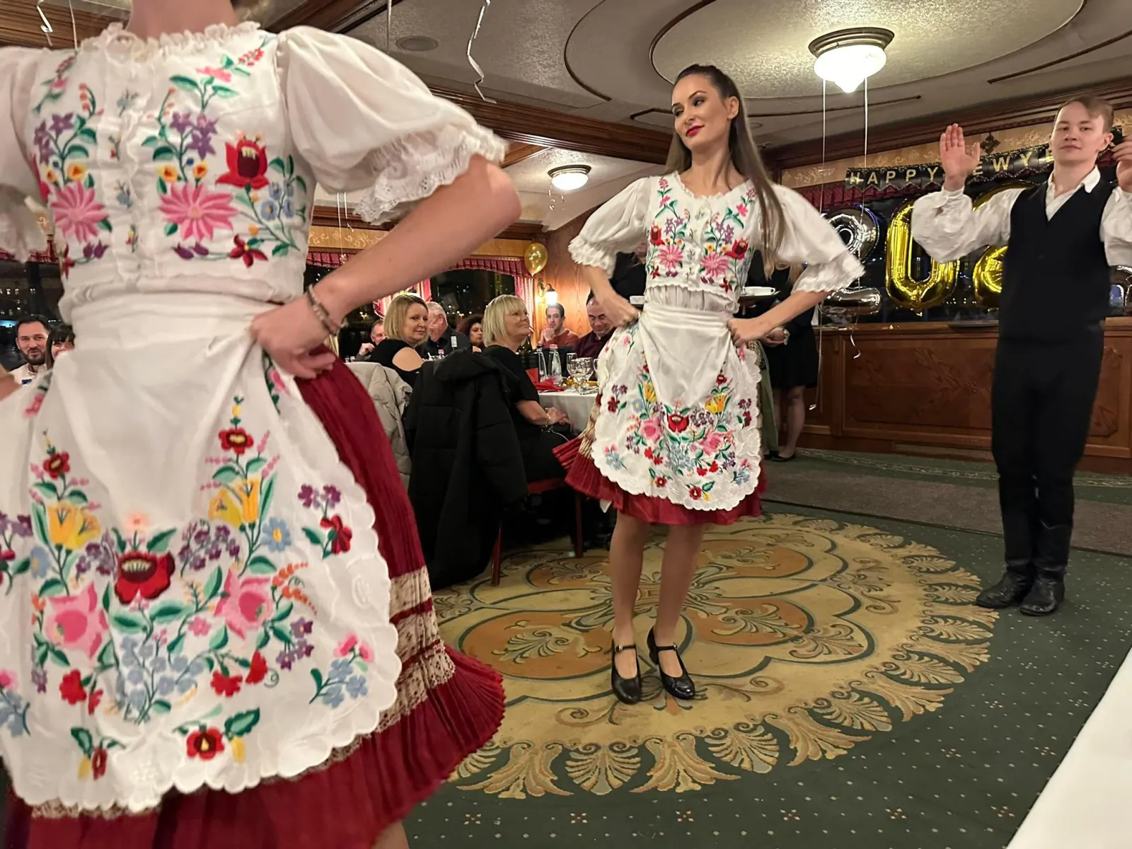 Folk dancers in embroidered costume performing on board