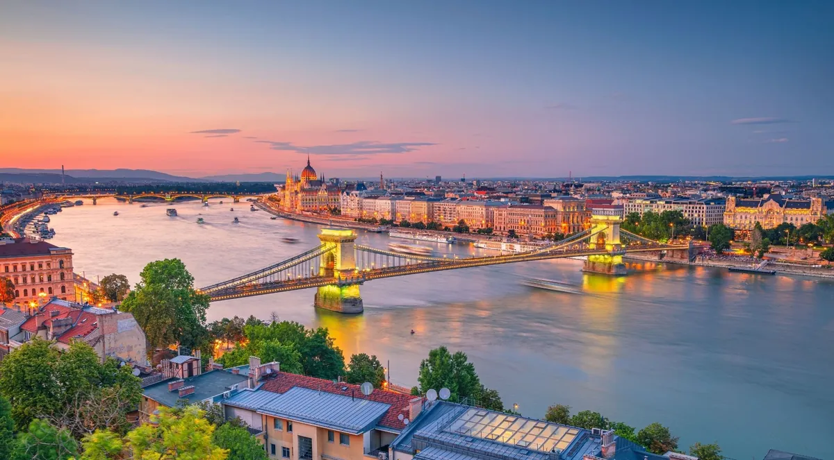 The Chain Bridge and the Parliament from the Buda hills at sunset, the lights coming on along the Danube